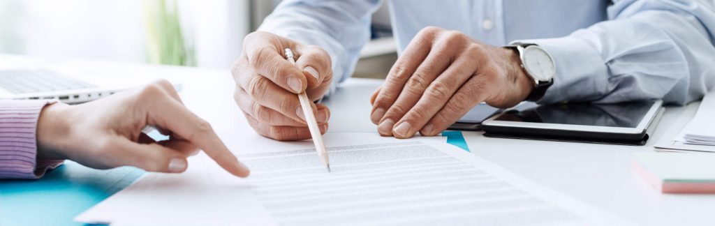 Menschen zeigen auf Vertragsdokument - bildlich für Vereinbarung Beratungshonorar in der Versicherungsberatung.