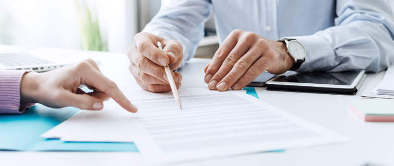 Hände mit Stift über Vertrag - bildlich für Honorarfragen bei der Versicherungsberatung